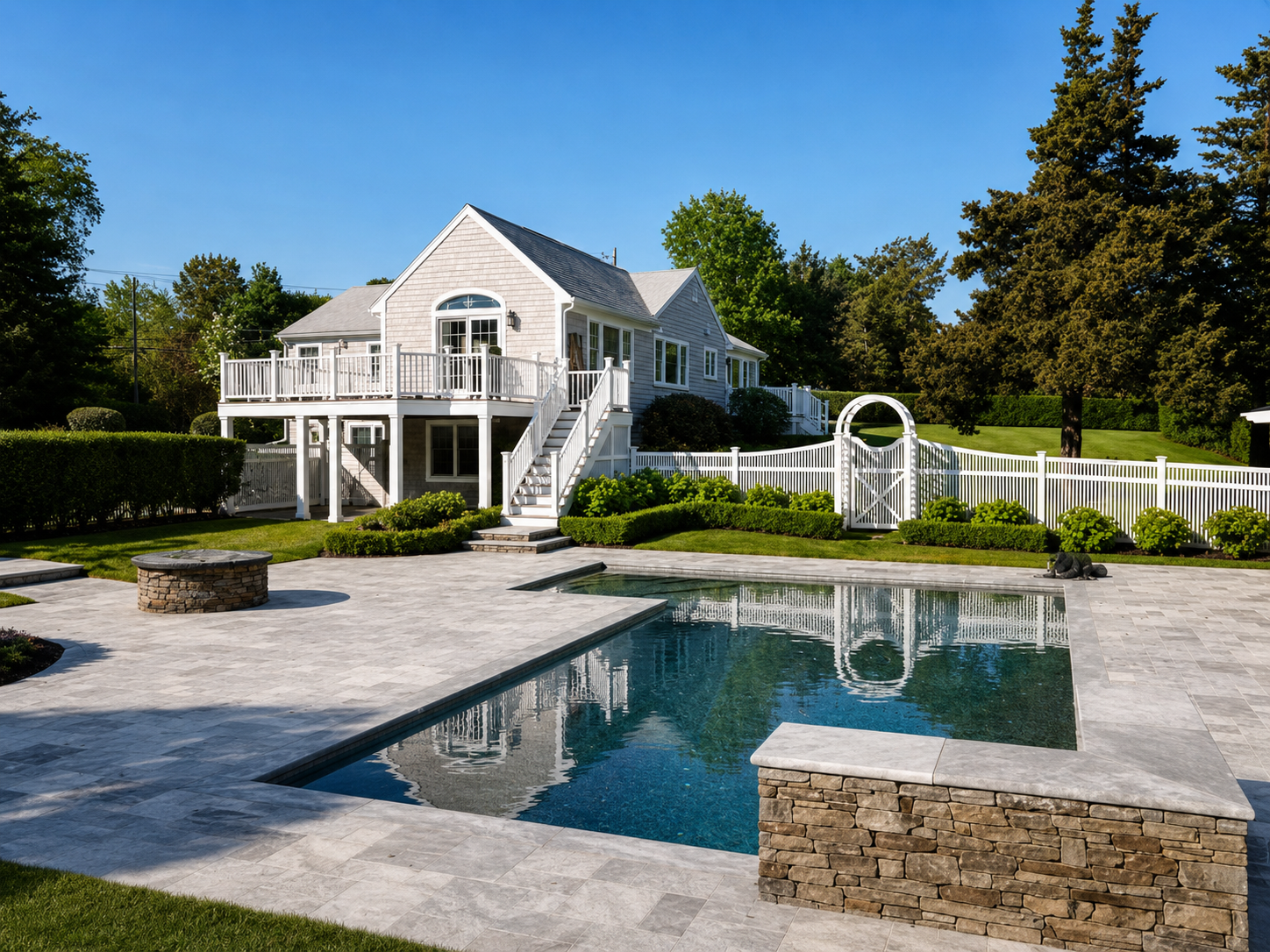 Completed Cape Cod home with pool, stone hardscape and raised exterior deck